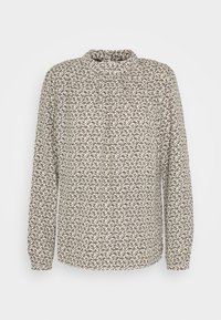Blouse à manches longues beige, arborant un motif abstrait noir et marron répétitif, col haut et tissu doux avec une légère texture.