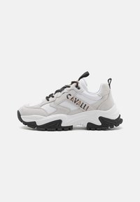 Masivne športne superge, ki združujejo belo usnje in sivo semiš, imajo črno gumijasto podplat, zavezovanje z vezalkami in logotipno podrobnost na strani.