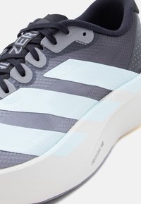 Κοντινή λήψη γκρι και ανοιχτό μπλε παπουτσιού τρεξίματος Adidas με μαύρα κορδόνια και λευκή σόλα με ετικέτα "Lightstrike Pro".