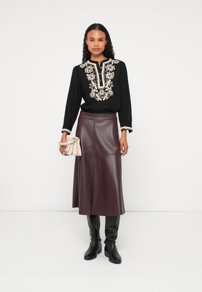 Čierna blúzka s kvetinovou výšivkou, dlhými rukávmi a výstrihom. Bordová midi sukňa z faux kože s priliehavým pásom. Čierne čižmy po kolená.