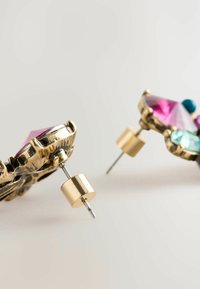 Ohrringe in Goldoptik mit facettierten rosafarbenen und türkisfarbenen Edelsteinen, die in einem blattähnlichen Design mit Metallbeschlägen und einer silbernen Nadel gefasst sind.