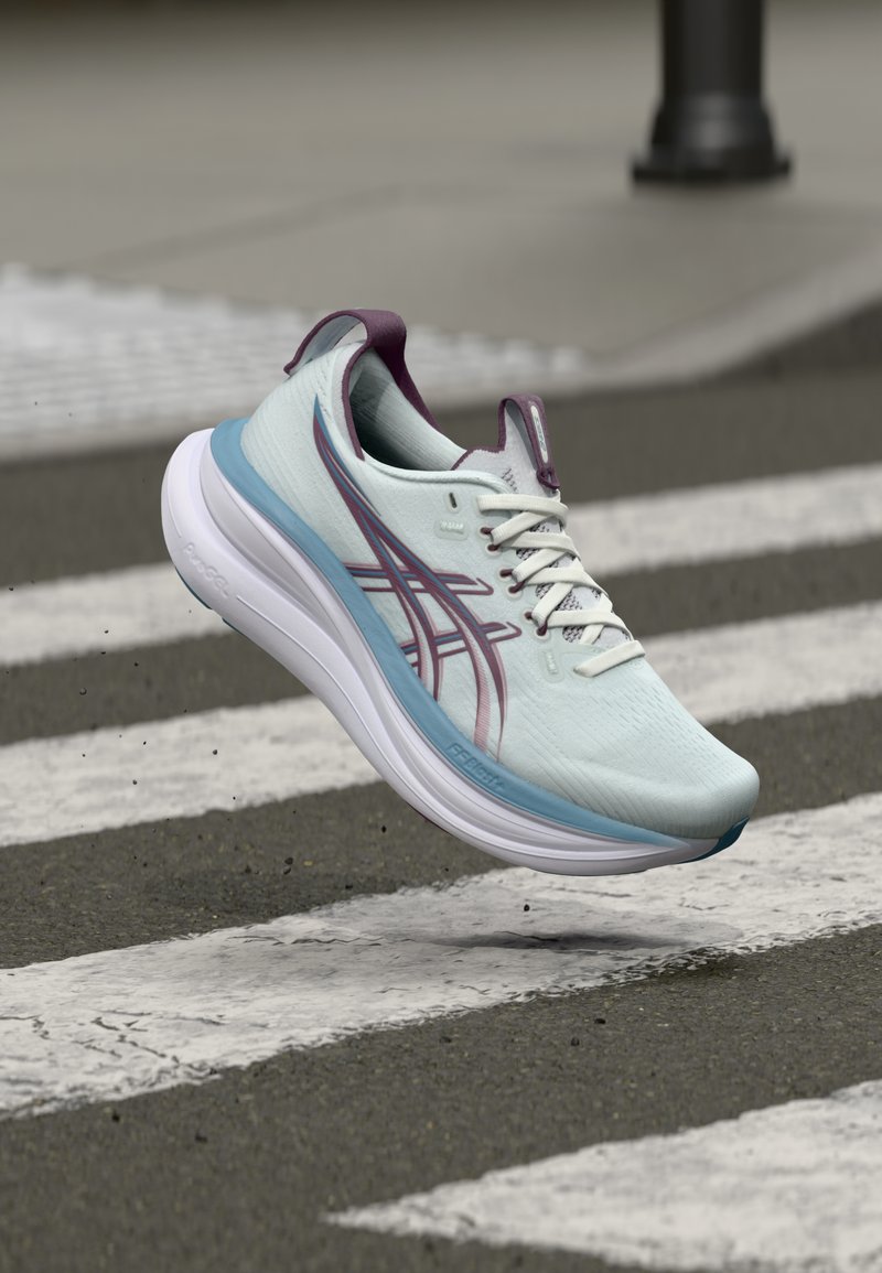 Světle modrá běžecká bota s fialovými akcenty, texturovaným svrškem a bílou stélkou. Disponuje elegantním designem, zavazováním na tkaničky a detailním logem.