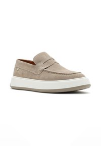 Beige suede slip-on shoe with a rounded toe and minimal stitching. Features a white rubber sole with a light brown accent.