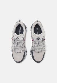 Zapatillas deportivas gris claro con parte superior de malla, acentos texturizados, suela negra contrastante y detalles en rosa en los cordones y la marca.