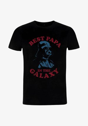 T-shirt en coton noir avec un graphique imprimé d'une figure casquée portant l'inscription "MEILLEUR PAPA DE LA GALAXIE" en lettres rouges et bleues.
