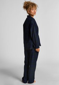 Marineblauw geblokt pyjama set van zachte stof. Langsleeve top met een knoopkraag, bijpassende broek met een ontspannen pasvorm en een geblokt patroon.