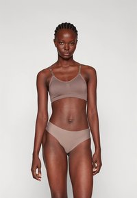 Soutien sem costuras castanho com alças ajustáveis e cuecas de bikini castanhas combinantes. Ambos têm uma textura suave e detalhes mínimos.