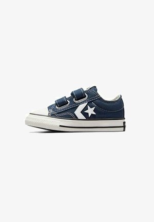Zapatillas de denim azul con logo de estrella blanca, dos correas de velcro, punta de goma blanca y suela a rayas negras. Diseño clásico de corte bajo.