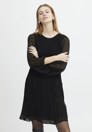 Schwarzes plissiertes Kleid mit rundem Ausschnitt und langen, durchsichtigen Ballonärmeln. Glatte Textur, knielanges Design, geraffte Taille.