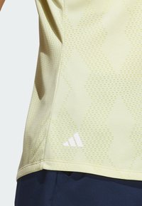 Lichtgele sportshirt met textuurpatroon met diamanten vormen, witte logo-accent aan de zoom en korte mouwen.