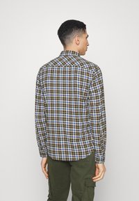 Camisa de cuadros de manga larga con una mezcla de cuadros en azul, verde y marrón, hecha de una tela ligera y con cuello abotonado.