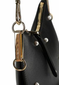 Borsa in pelle nera con finiture dorate, inclusi un moschettone e anelli decorativi, arricchita da perle ornamentali.