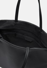 Czarna skórzana torba na ramię z dwoma długimi uchwytami. Wnętrze wyposażone jest w kieszeń na zamek błyskawiczny i gładką teksturę, podkreślając jej przestronny design.