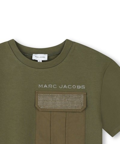 Maglietta verde oliva con scollo a girocollo, dotata di una tasca frontale con una patta borchiata in metallo e la scritta "MARC JACOBS" sopra.