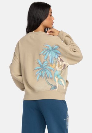 Beige sweatshirt met een grafisch ontwerp van palmbomen en een vrouw op de rug, met blauwe en groene accenten. Vrije pasvorm met geribbelde manchetten.