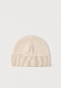 Căciulă bej tricotată, cu mansetă pliabilă tip rib, textură netedă și design cu partea superioară rotunjită. Potrivită pentru căldură și confort în condiții de vreme rece.