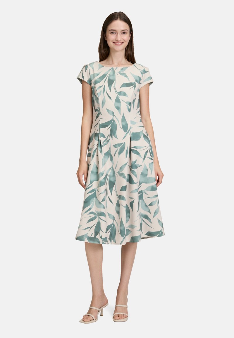 Blumenkleid mit kurzen Ärmeln, cremefarbenem Hintergrund und türkisfarbenen Blattmustern. A-Linien-Silhouette, midilang, glatter Stoff.