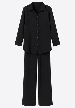 Zwart loungepak bestaande uit een blouse met knopen, lange mouwen en een kraag, en losse broek, gemaakt van een textuurstof.