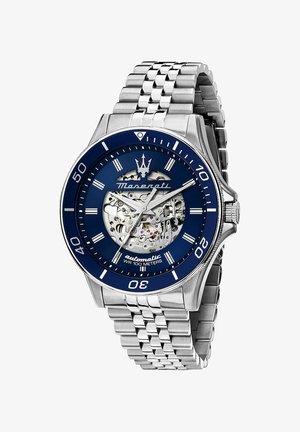 Silberner Edelstahl-Automatikuhren mit blauem Zifferblatt, Skelett-Display und strukturiertem Armband. Wasserdicht bis 100 Meter.