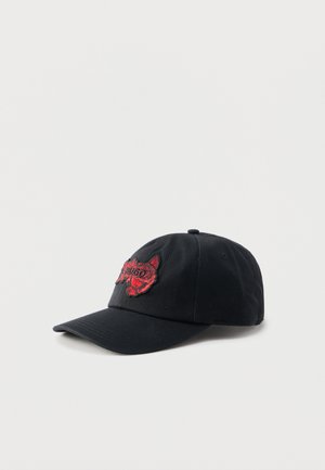 Mustast baseballi nokamüts kumerate äärega, mille esipaneelil on punase tikitud tiigri pea ja tekst "HUGO".