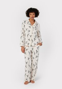 Cotton pajama set featuring a cream background with black bird prints, long sleeves, button-up top, and matching elasticated pants.