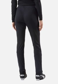 Pantaloni atletici neri in tessuto liscio ed elastico. Presentano una gamba affusolata e cerniere alle caviglie per facilitare la vestibilità.