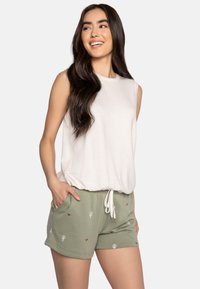 Witte mouwloze top met een ronde zoom, gecombineerd met groene shorts met cactus- en hartpatronen, een elastische tailleband en zijzakken.