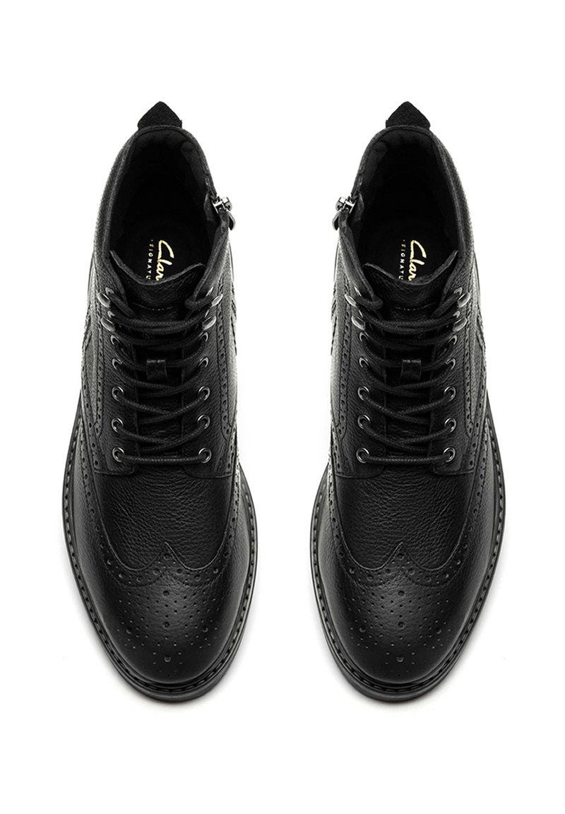 Scarpe brogue in pelle nera con superficie texturizzata, punta affusolata e perforazioni decorative, dotate di un design con lacci e cerniera laterale.