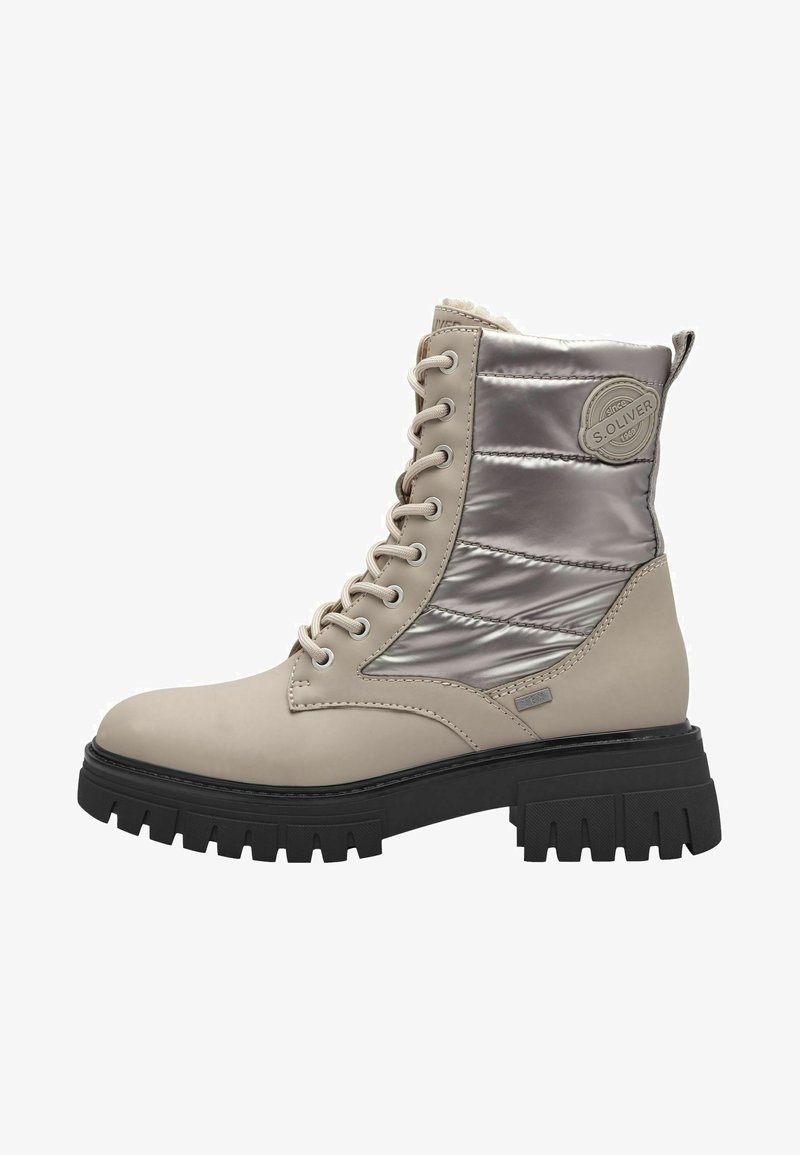 Botas de tobillo beige con cordones, panel textil plateado brillante, suela negra texturizada y logotipo destacado de la marca en el lateral.