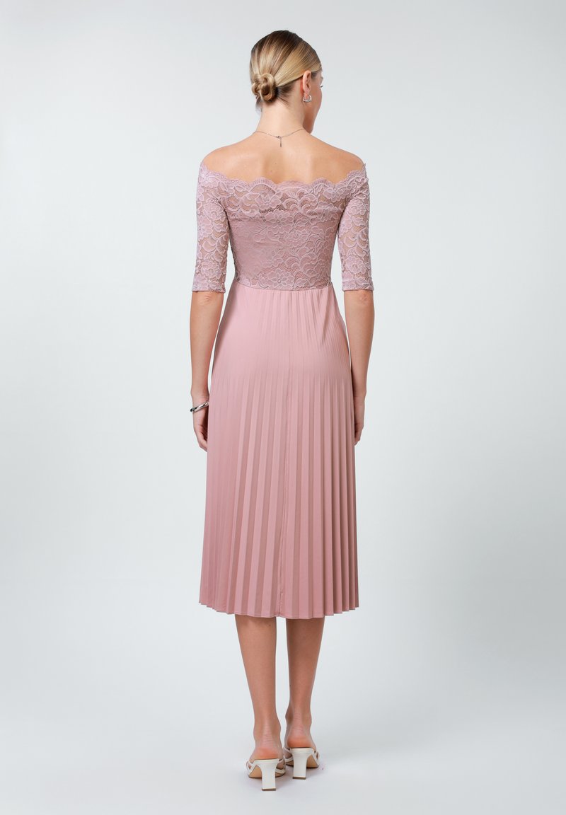 Robe rose poussiéreuse avec un corsage en dentelle, des manches trois-quarts et une jupe plissée. Encolure décolletée et texture de tissu lisse.