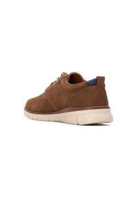 Zapatos de ante marrón con punta redonda, suela beige y acento azul marino en el talón. Presentan cordones para un ajuste seguro. Textura suave.