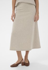 Gai bēšs midi svārki no mīksta, gluda auduma ar brīvu piegriezumu. Saskaņoti ar brūniem austiem slingu apaviem ar masīlu papēdi.