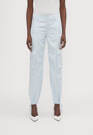 Light blue cargo pants with elastic cuffs, multiple side pockets, and a smooth, shiny texture. Paired with white heels for contrast.