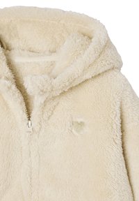 Fleece-Partial Hoodie in cremigem Beige mit einer weichen, strukturierten Oberfläche; verfügt über ein kleines Herz-Patch und eine Zugkordelkapuze.