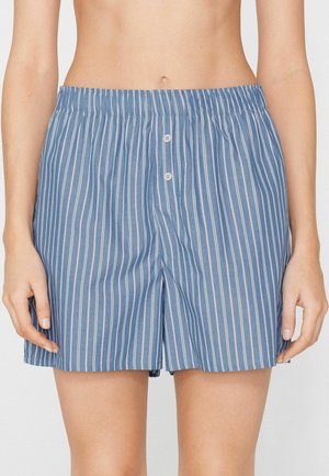 Blaue und weiße vertikal gestreifte Baumwoll-Boxershorts mit elastischem Bund und zwei weißen Vorderknöpfen am Mittelteil einer Person.