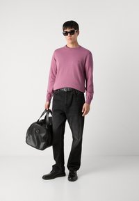 Svijetlopurpurasti džemper dugih rukava, crne traperice, crni pojas, crne tenisice i crna kožna torba. Minimalistički dizajn i čiste linije.