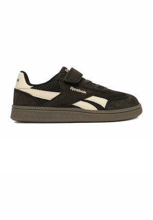 Zapatilla Reebok en blanco y negro con detalles de malla y ante, tira de Velcro y suela de goma texturizada, mostrada de perfil.