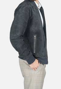 Schmal geschnittene Bomberjacke aus dunkelgrauem Wildleder, mit geripptem Kragen, seitlicher Reißverschlusstasche und strukturiertem Stoff.