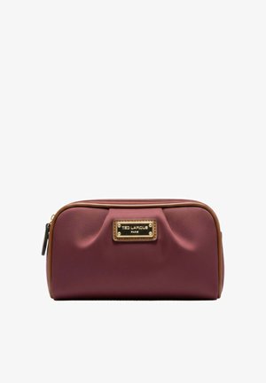 Trousse de toilette rectangulaire bordeaux avec garniture marron, plis avant, plaque logo dorée et fermeture éclair sur fond blanc.