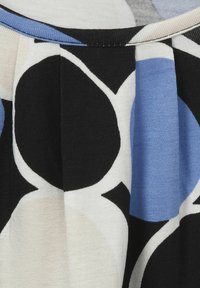 Mehrfarbiger Kleidungsstoff mit großen geometrischen Formen in Schwarz, Blau und Beige, mit einer weichen Textur und plissierter Gestaltung.