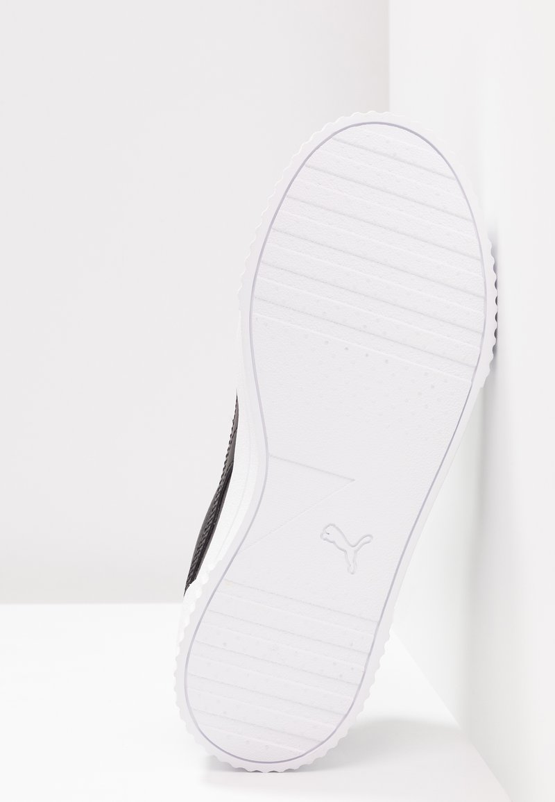 Chaussure de sport noire avec une tige texturée, dotée d'une semelle en caoutchouc blanche avec des stries et d'un logo en relief sur le côté.