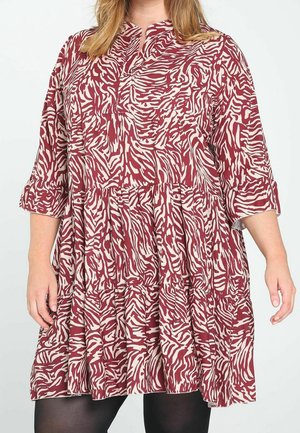 Vestido estampado de cebra en rojo y crema con diseño en capas, mangas tres cuartos y escote con botones. Hecho de tela ligera.