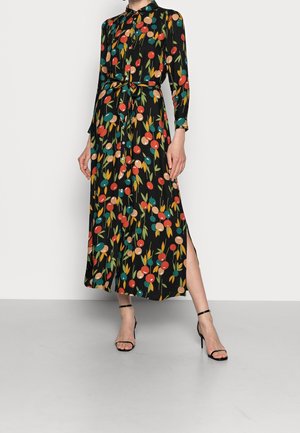 Femme portant une robe midi noire à boutons avec un imprimé floral circulaire coloré, des manches longues, une ceinture à la taille, une fente latérale et des sandales à talons hauts noires.