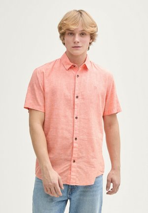 Chemise à manches courtes, à boutons, de couleur corail clair, fabriquée en tissu texturé avec des boutons marron et un petit logo sur la poitrine.