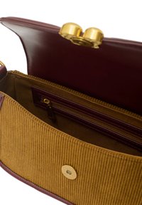 Burgundy läderhandväska inuti med en senapsgul corduroy-del, har ett dragkedjefack och giltiga hårdvarustängning.