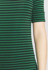 Kortärmad topp i stretchig tyg med svarta och gröna horisontella ränder, rundad halsringning och figurnära passform.