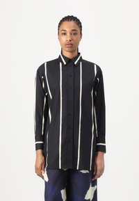 Black button-up shirt with white vertical stripes, long sleeves, and a classic collar; made of smooth fabric with a relaxed fit.