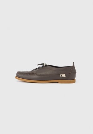 Brown leather shoe with a textured upper, lace-up design, and a rubber sole. Features a metallic accent on the side. Low-profile shape.