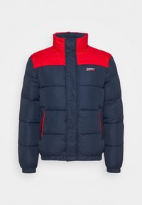 Marinblå och röd vadderad jacka med ståkrage, tryckknappsstängning, sidofickor och Tommy Jeans-logotyp på bröstet.