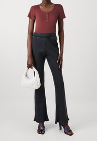 Ribbad vinröd kortärmad bodysuit, kombinerad med svarta texturerade utsvängda byxor. En vit kviltad handväska och lila klacksandaler fulländar looken.